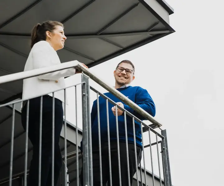 Zwei Kollegen stehen auf der Treppe und besprechen den Bewerbungsprozess