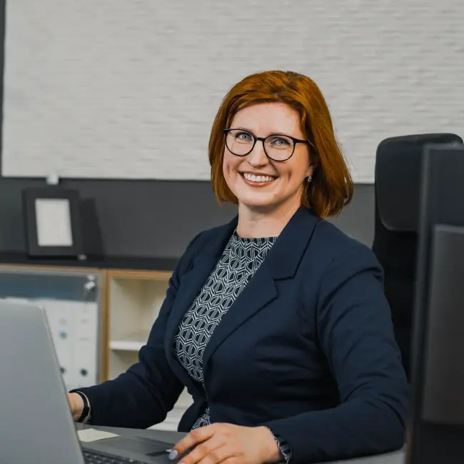 Frau sitzt am Schreibtisch an einem Laptop